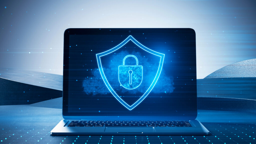 Close up of laptop with glowing shield hologram on screen. Blurry desktop background. Secure, protection, safety and web security concept. 3D Rendering